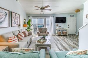 a living room with a couch and a tv at Salt and Light Oceanfront Condo with Pool and Elevator in Ocean Isle Beach