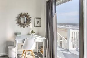 a room with a table and a view of the beach at Salt and Light Oceanfront Condo with Pool and Elevator in Ocean Isle Beach