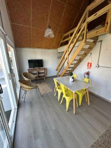 a dining room with a table and yellow chairs at Kanaloah Lodge & Cabins in Punta Del Diablo