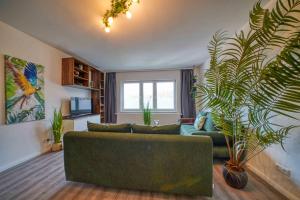 ein Wohnzimmer mit einer grünen Couch und Pflanzen in der Unterkunft Zuarin Schlossblick - Ganzes Apartment direkt am Schlossgarten von Schwerin mit Dschungel-Feeling - Parkplatz auf Anfrage vorhanden in Schwerin