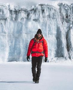 um homem andando na neve em frente a uma cachoeira em Mogli Adventure safari em Moshi