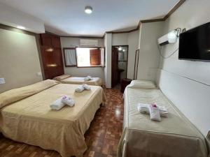 a hotel room with two beds and a flat screen tv at Hotel Santander in Termas de Río Hondo