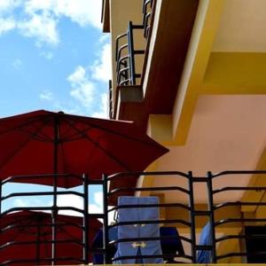 ein roter Regenschirm und Stühle neben einem Gebäude in der Unterkunft One Love Hotel in Kigali
