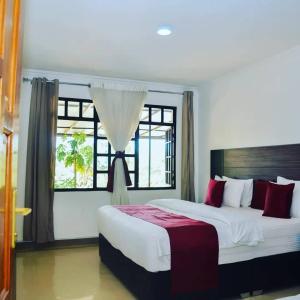 um quarto com uma cama grande e uma janela em One Love Hotel em Kigali