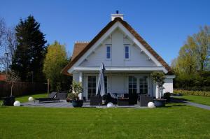 a white house with a flag in the yard at Golden Wellness Villa Noordwijk in Noordwijk