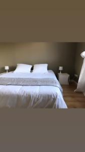 una camera da letto con letto, lenzuola e cuscini bianchi di Gîte "Le Millésime 61" a Flavigny