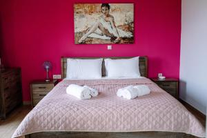 a bedroom with a bed with a pink wall at Konatsi Luxury Apartments in Tiros