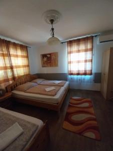 a bedroom with two beds and a rug and windows at Lipták Vendégház in Tokaj