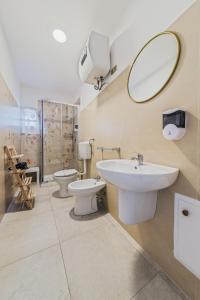 La salle de bains est pourvue de 2 toilettes, d'un lavabo et d'un miroir. dans l'établissement Voilà Rooms Guest House, à Terrasini