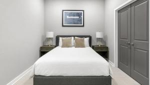1 dormitorio blanco con 1 cama con 2 mesitas de noche y 2 lámparas en Landing Modern Apartment with Amazing Amenities (ID1801X69), en Birmingham