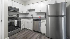 a kitchen with white cabinets and a stainless steel refrigerator at Landing Modern Apartment with Amazing Amenities ID1803X75 in Homewood