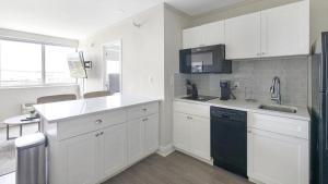 een keuken met witte kasten en een zwart apparaat bij Landing Modern Apartment with Amazing Amenities ID1804X44 in St Petersburg