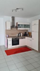 a kitchen with white cabinets and a red rug at Ruhige Ferienwohnung am Rande des Nordschwarzwalds in Straubenhardt