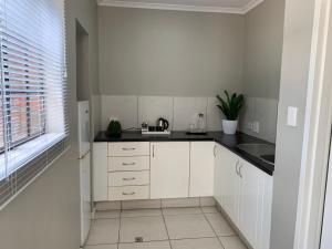 a kitchen with white cabinets and a black counter top at The Leslie - Bed & Breakfast in Blantyre