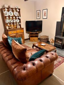 a living room with a brown leather couch and a television at Historic cottage with oak beams & period charm in Llangadog