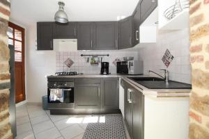 a kitchen with gray cabinets and a stove at Maison pour s’évader à la campagne in Trancault