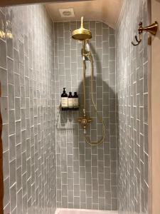 a bathroom with a shower with blue tiles at Historic cottage with oak beams & period charm in Llangadog