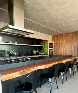 eine Küche mit einer langen Bar mit schwarzen Stühlen in der Unterkunft LIV 404 - Maceió - Ponta Verde in Maceió