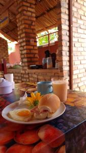 a table with a plate of breakfast food and a glass of milk at Pousada Brasil - São Miguel do Gostoso in São Miguel do Gostoso
