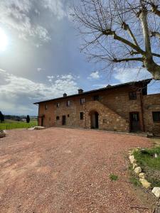 a large brick building with a gravel driveway at Tenuta i 4 venti in Collesalvetti