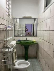 uma casa de banho com um lavatório verde e um WC em RÉSIDENCE VGP LOGPOM em Douala