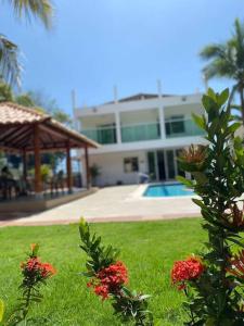 una casa con un patio con flores en el césped en Palma House - Cabaña con piscina, en Tubará