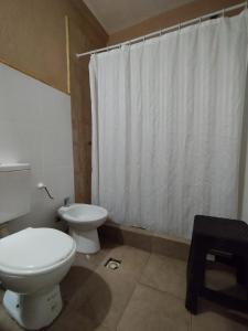 uma casa de banho com um WC e uma cortina de chuveiro branca em La Morada Hostal em Cafayate