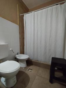 a bathroom with a toilet and a white shower curtain at La Morada Hostal in Cafayate +15 photos