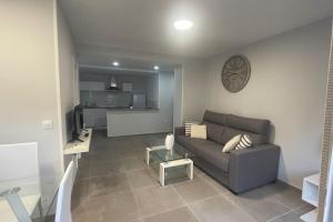 - un salon avec un canapé et un réveil sur le mur dans l'établissement Apartamento moderno y coqueto en playa San Juan, à Alicante