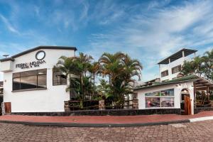 un bâtiment blanc avec des palmiers devant lui dans l'établissement Fernandina Hotel & Spa, à Puerto Ayora