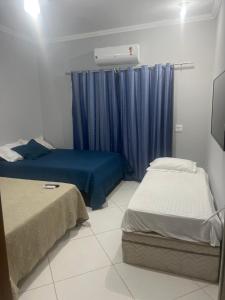 ein Schlafzimmer mit 2 Betten und einem blauen Vorhang in der Unterkunft Casa traineras in Arraial do Cabo