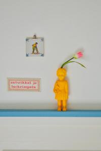a yellow figurine standing on a shelf with a flower at Hotel Greate Pier in Kimswerd