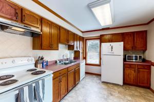a kitchen with wooden cabinets and a white refrigerator at Vitamin Beach 12 in Avon