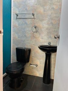 La salle de bains est pourvue de toilettes noires et d'un lavabo. dans l'établissement Punta Arena EcoHostal & EcoFit - Your Eco-Friendly Oasis 02, à Playa Punta Arena