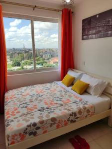 a bedroom with a bed with a window and red curtains at Anga Nest a chic One-Bedroom Ngong Road in Nairobi