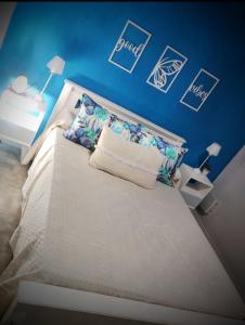 - une chambre avec un lit blanc et un mur bleu dans l'établissement Amapola, à Balneario Mar Chiquita