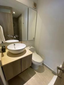 ein Badezimmer mit einem Waschbecken, einem WC und einem Spiegel in der Unterkunft Apartamento frente al Mar Cartagena in Cartagena de Indias