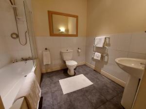 a bathroom with a tub and a toilet and a sink at The Coach and Horses in Winchester