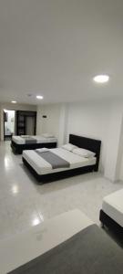 two beds in a room with white walls and white floors at Hotel Paradise Lleras in Medellín