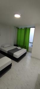 a bedroom with two beds and a green curtain at Hotel Paradise Lleras in Medellín