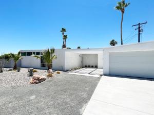 a white building with a garage and palm trees at Super Cute room in Architectural Home in Palm Springs