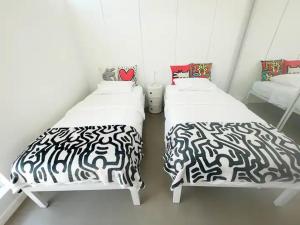 two beds in a small room with black and white sheets at Super Cute room in Architectural Home in Palm Springs