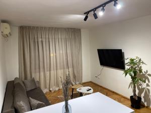 ein Wohnzimmer mit einem Sofa und einem Flachbild-TV in der Unterkunft Cozy Apartment, in the center of Tirana in Tirana