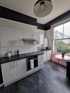 a kitchen with white cabinets and a table and a window at Lovely One Bed Apartment in St Leonards in St. Leonards