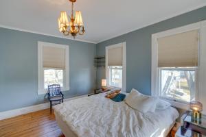 a bedroom with a bed with a chandelier and two windows at Pet-Friendly Hudson Home Near Won Dharma Center! in Hudson