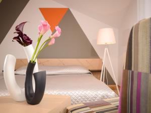 a room with a bed and a vase with flowers on a table at Mans Nams in Saldus