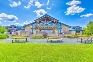 a home with picnic tables in front of a building at Arrowhead Lake Retreat with Private Indoor Pool! in Pocono Lake