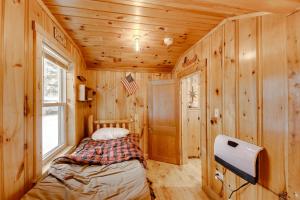 a small bedroom with a bed in a wooden cabin at Lovely Maine Cabin with Deck, Gas Grill and Fire Pit! in Casco
