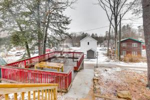a house with a red deck in the snow at Lovely Maine Cabin with Deck, Gas Grill and Fire Pit! in Casco