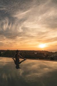 een persoon aan de rand van een zwembad bij zonsondergang bij Villa Macarena Apartamentos Boutique - Adults Only in Puerto Escondido
